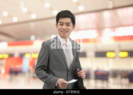 Imprenditore giovane azienda biglietto presso l'aeroporto, Pechino, Cina Foto Stock