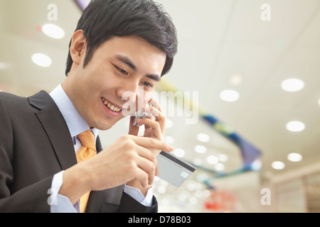 Imprenditore sul telefono, controllare il biglietto Foto Stock