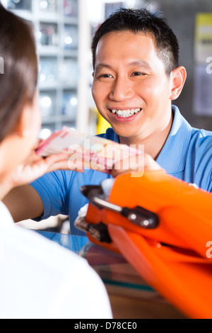 Asian il cliente in un negozio o un negozio per i subacquei, egli è il noleggio o acquisto di pinne per nuoto Foto Stock