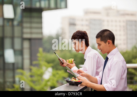 Due giovani imprenditori lavorano all'aperto e mangiare Foto Stock