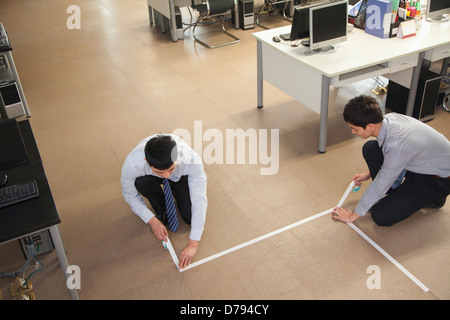 Due giovani imprenditori la nastratura fino al pavimento in ufficio Foto Stock