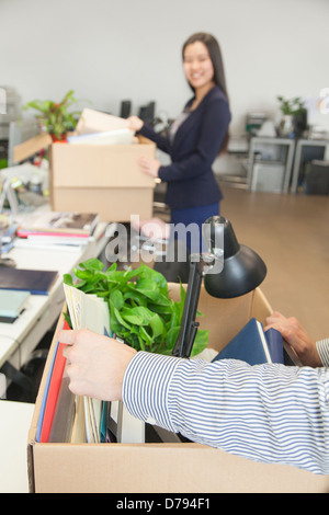 Due giovani uomini di affari che trasportano le scatole di articoli per ufficio Foto Stock