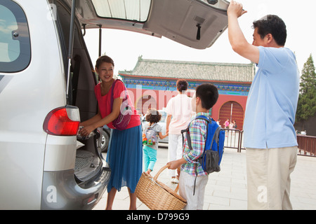 Famiglia prendendo roba fuori dall'auto, preparazione per picnic Foto Stock