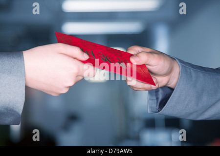 Close up sulle mani lo scambio di un rosso cinese di nuovo anni busta Foto Stock