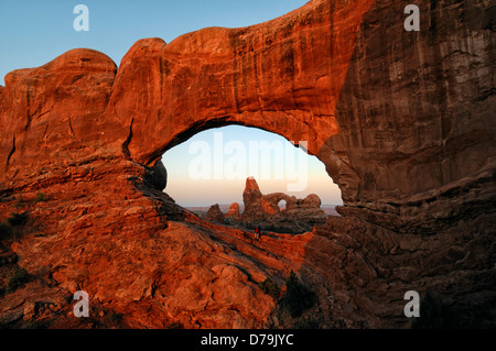 La torretta Arch bagliore rosso incandescente al sunrise visto attraverso la finestra del Nord Arch Arches National Park nello Utah Stati Uniti arenaria Foto Stock