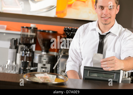 Bello sorridente cameriere maschio dando il ricevimento in corone ceche nel pub Foto Stock