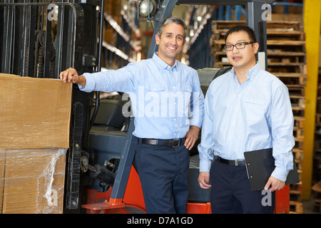 Ritratto di imprenditori con il carrello elevatore a forche in magazzino Foto Stock
