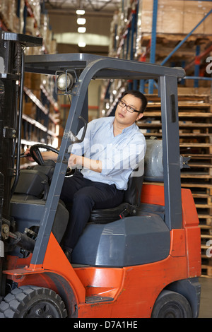 Uomo alla guida carrello elevatore a forche in magazzino Foto Stock