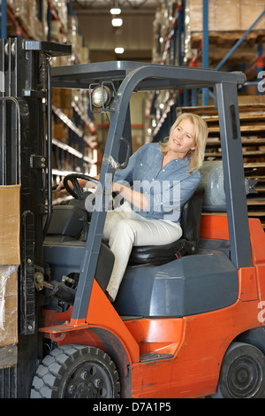 Donna alla guida carrello elevatore a forche in magazzino Foto Stock