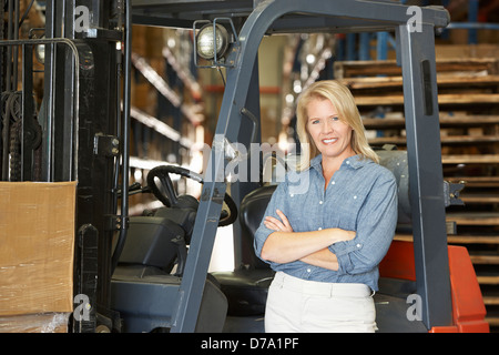 Ritratto di donna con il carrello elevatore a forche in magazzino Foto Stock