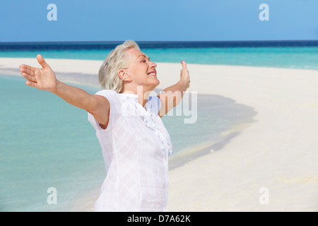 Senior donna con le braccia aperte sulla bella spiaggia Foto Stock