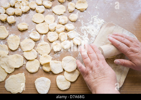 La nonna mani stendete la pasta su un tavolo di legno Foto Stock