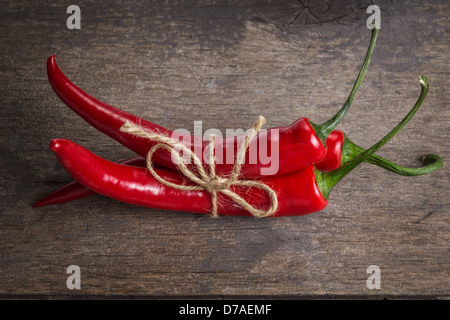 Legato peperoncino rosso sul vecchio tavolo in legno con graffi Foto Stock