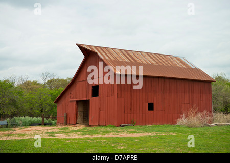 Un granaio rosso con un arrugginito tetto dello stagno su una fattoria in Oklahoma. Foto Stock