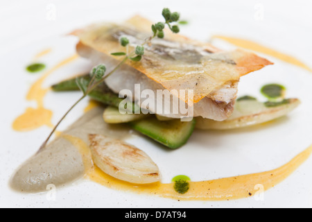 Filetto di branzino con pasta di patate salvia pepe timo salsa arancione guarnita con zucchine Foto Stock