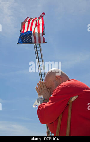 Warren, Michigan, Stati Uniti d'America. Poggiando su sue stampelle, Hiram Squires prega durante l annuale Giornata Nazionale di Preghiera rispetto al city hall. Una bandiera americana è appeso sopra di lui su una città camion dei pompieri. Credito: Jim West / Alamy Live News Foto Stock