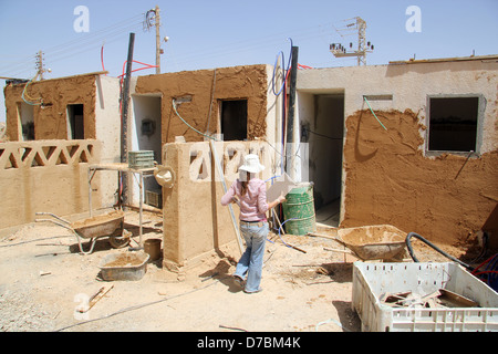 Edificio ecologico nel Kibbutz Neot Semadar utilizzando locale di fango nel deserto per applicare il cerotto alla parete, nel Negev, a sud di Israele Foto Stock