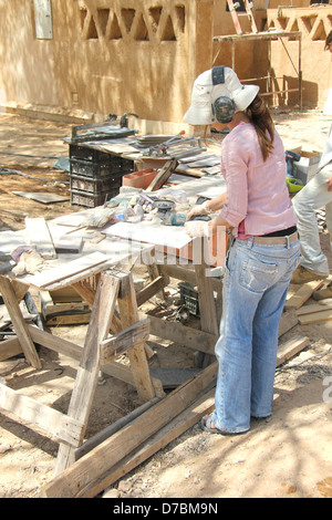 Lavoratore di sesso femminile che impegnato nella costruzione ecologica nel Kibbutz Neot Semadar nel Negev, a sud di Israele Foto Stock