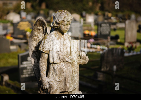 Angelo di pietra su una lapide in un cimitero Foto Stock