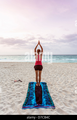 Messico, Playa del Carmen, giovane donna a praticare yoga sulla spiaggia al sorgere del sole Foto Stock