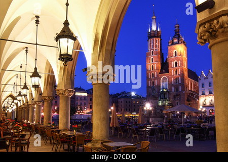 La Piazza del Mercato di Cracovia al crepuscolo e basilica dell'Assunzione di Nostra Signora (St Mary's) visto dal mercato arcade. Polonia Foto Stock