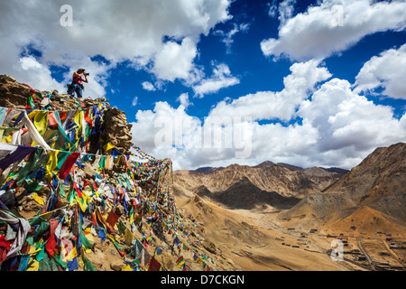 Fotografo di viaggio per scattare delle foto in Himalaya montagne sulla scogliera con la preghiera buddista bandiere. Leh, Ladakh, Jammu e Kashmir Foto Stock