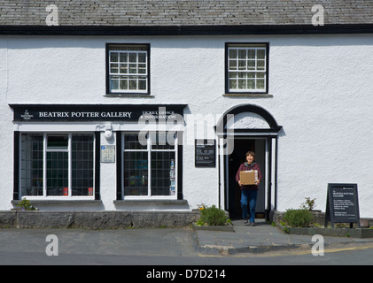 Giovane donna asiatica che trasportano box out of Beatrix Potter Gallery, Hawkshead, Parco Nazionale del Distretto dei Laghi, Cumbria, England Regno Unito Foto Stock