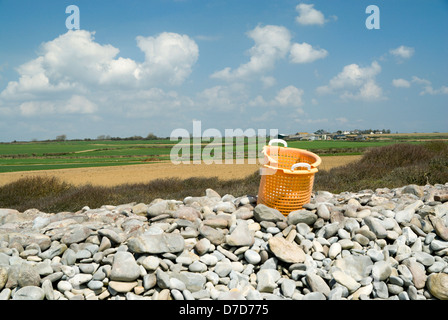 Giallo cesto in plastica, sulla spiaggia di ciottoli, di Aberthaw, Glamorgan Heritage Costa, Vale of Glamorgan, Galles del Sud. Foto Stock