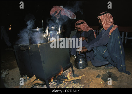 I beduini nomadi che indossa un rosso e bianco a scacchi keffiyeh preparazione del tè in Wadi Rum desert conosciuta anche come la Valle della Luna in Giordania Meridionale Foto Stock