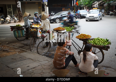 I venditori ambulanti che vendono i loro frutti da loro biciclette nel quartiere vecchio di Hanoi, Vietnam Foto Stock