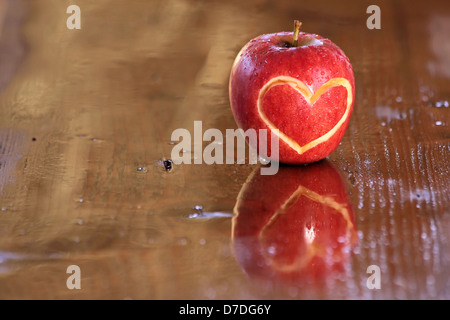 Rosso apple bagnato con forma di cuore sulla scrivania in legno