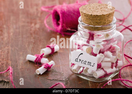 Sogni scritto su un bianco carta arrotolata in un vasetto di vetro su rustiche in legno vintage sfondo, sognando il concetto di ottimismo Foto Stock