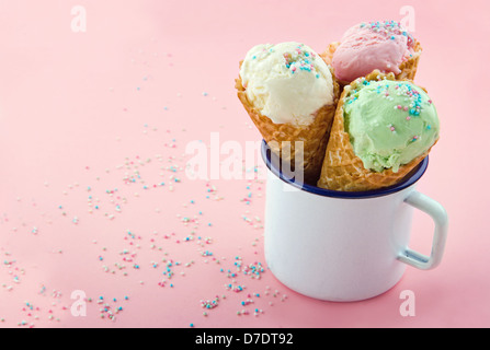 Coni gelato con spruzza su sfondo rosa e spazio di copia Foto Stock