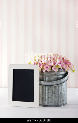 Pink hydrangea fiori in un vaso di metallo su vintage sfondo con lavagna vuota per spazio di copia Foto Stock