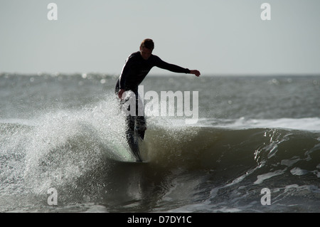 Un pennacchio di spray solleva la punta della tavola in un classico appendere cinque in un Gower sessione di navigazione in Galles, Regno Unito Foto Stock