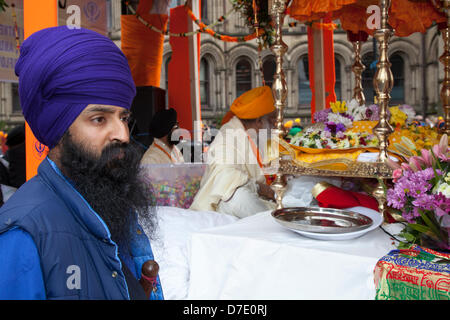 Manchester, Regno Unito. Il 5 maggio, 2013. Seduto Guru sikh e una Mail-placcati funzionario su decorate galleggiante sul più importante celebrazione aisakhi nel calendario Sikh segnata dalla comunità sikh di Greater Manchester, con la loro annuale Nagar Kirtan processione attraverso le vie della città. Il Nagar Kirtan è a colori, celebrazione e adorazione ed è un invito per tutti indipendentemente dalla casta, di religione e di credo per unire i sikh nel celebrare la loro religione e cultura. Credito: Mar fotografico/Alamy Live News Foto Stock