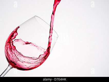 Versando il vino in un vetro di composizione diagonale e sfondo bianco Foto Stock