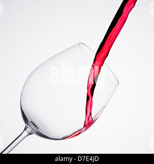 Versando il vino in un vetro di composizione diagonale e sfondo bianco. La foto viene scattata in formato quadrato Foto Stock