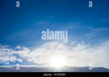 Sun impostazione/crescente dietro una coltre di nube all'orizzonte. Foto Stock