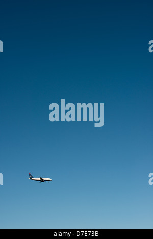 Un US Airways arriva a getto a terra con la sua landing gear down, volare contro un bel cielo blu chiaro. Foto Stock