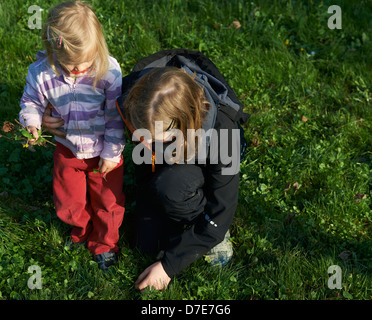 Due bambini bionda ragazze giocare con giardino di erba e fiori in estate Foto Stock