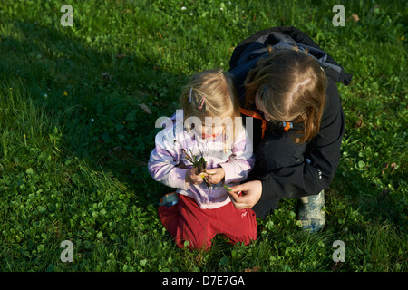 Due bambini bionda ragazze giocare con giardino di erba e fiori in estate Foto Stock