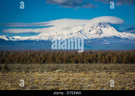 Nuvole lenticolari passando sopra il picco di rotture di Top montagne delle Sorelle deserto di Oregon Foto Stock