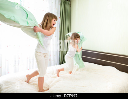 Bambine combattimenti utilizzando cuscini in camera da letto Foto Stock