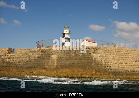 Un faro e un tratto delle mura della vecchia città di Acri, visto dal mare. Foto Stock