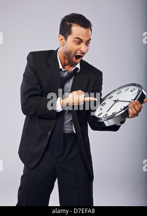 Imprenditore arrabbiato grida e puntando a un orologio Foto Stock