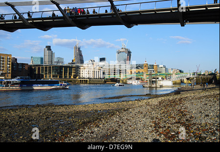 Vista della città di Londra dalla riva del tamigi,sotto il Millennium Bridge a bassa marea Foto Stock