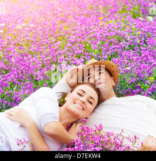 Giovane famiglia felice che stabilisce sul fresco prato di lavanda, avvolgente all'aperto durante la stagione estiva, del romanticismo e del concetto di amore Foto Stock