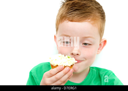 Bello piccolo ragazzo di mangiare un fresco bicchiere di crema torta con faccia sporchi Foto Stock