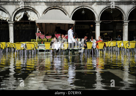 Vista di un Caffe terrazza con i clienti allagato da "Aqua Alta' Piazza San Marco, Venezia, Italia. Foto Stock